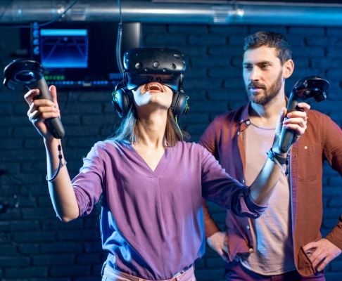 woman-trying-virtual-reality-with-man-assistant-e1653826383267